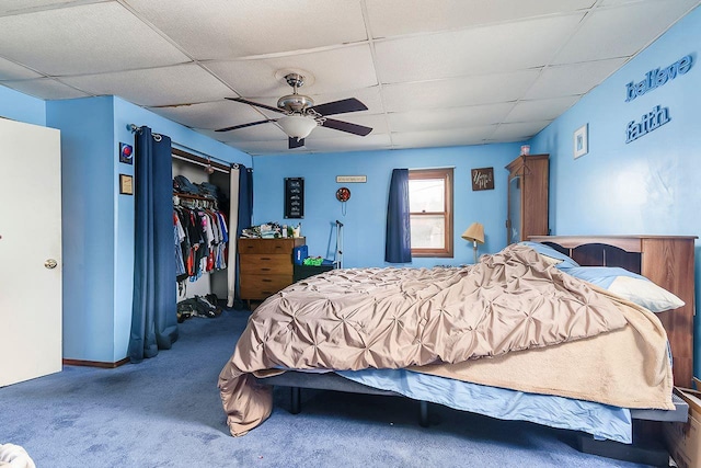 carpeted bedroom with a paneled ceiling, a closet, and ceiling fan