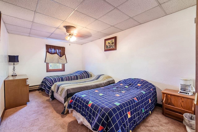 carpeted bedroom featuring a drop ceiling, baseboard heating, and ceiling fan