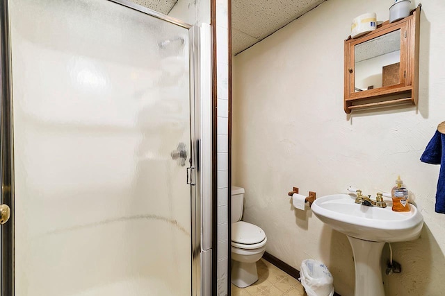 bathroom with a paneled ceiling, toilet, and a shower with door