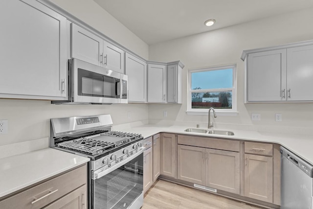 kitchen featuring gray cabinets, sink, stainless steel appliances, and light hardwood / wood-style flooring