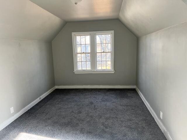 additional living space with vaulted ceiling and dark colored carpet