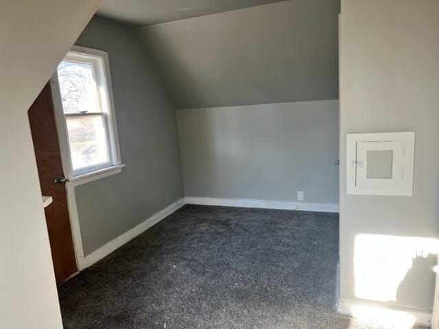 additional living space with dark carpet and vaulted ceiling