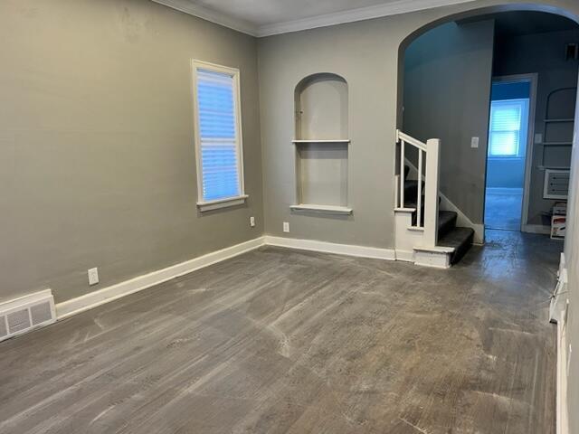 spare room featuring built in features and crown molding