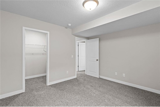 unfurnished bedroom featuring a walk in closet, carpet flooring, a closet, and a textured ceiling