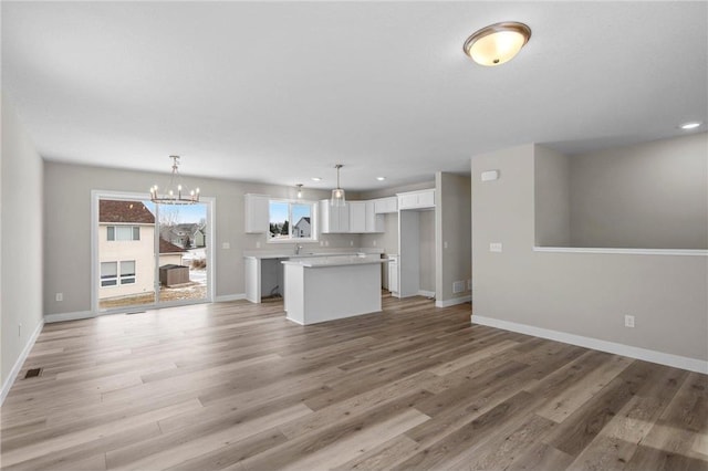 unfurnished living room with a notable chandelier and light wood-type flooring