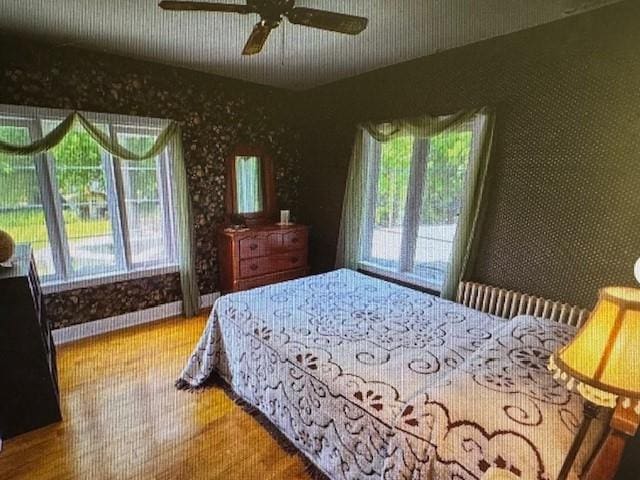 bedroom featuring ceiling fan, access to exterior, multiple windows, and hardwood / wood-style floors