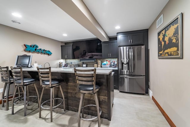 kitchen with tasteful backsplash, a breakfast bar, a center island, and stainless steel refrigerator with ice dispenser