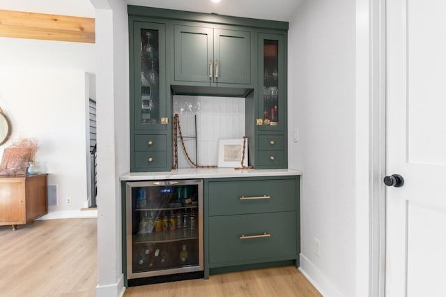 bar with green cabinets, light hardwood / wood-style floors, and beverage cooler