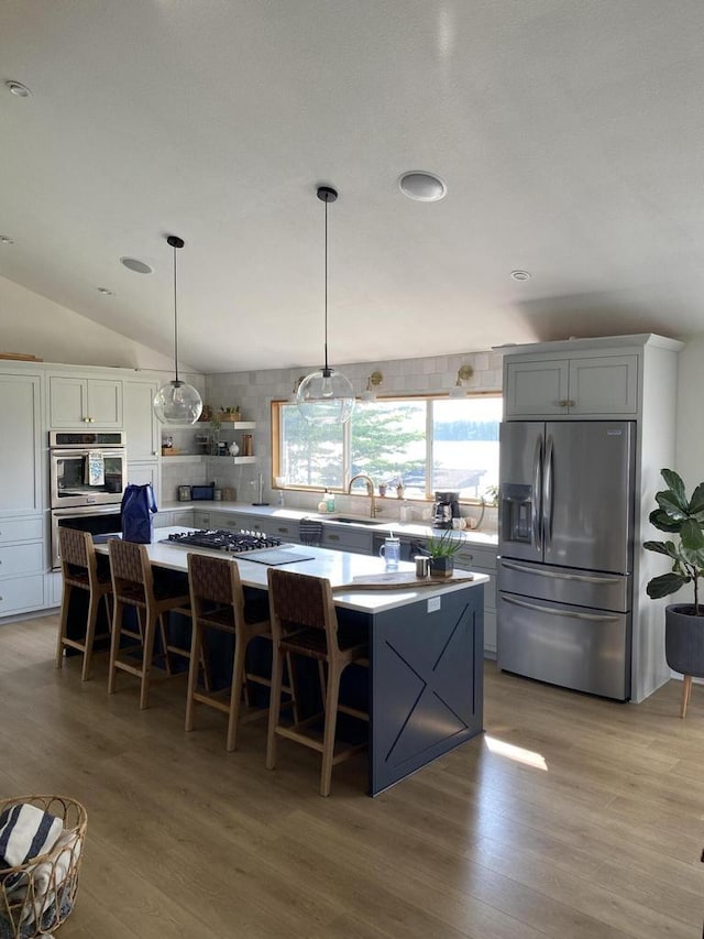 kitchen featuring appliances with stainless steel finishes, a center island, decorative light fixtures, and a kitchen breakfast bar