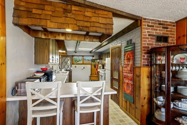 kitchen with kitchen peninsula, a kitchen breakfast bar, brick wall, and sink