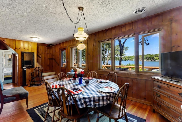 dining room with hardwood / wood-style floors, a textured ceiling, and wooden walls