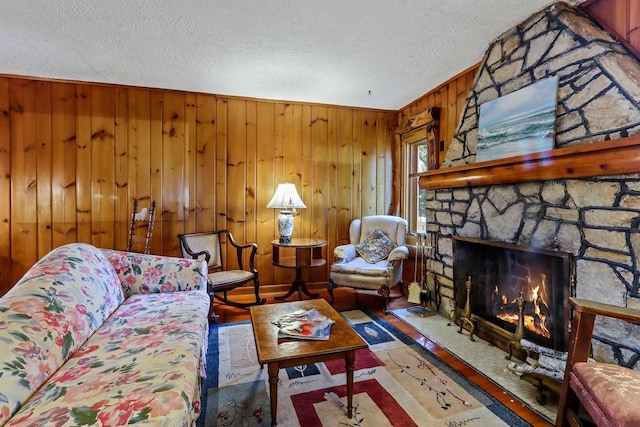 living room with wood walls, a fireplace, and a textured ceiling