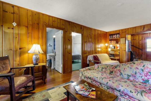 bedroom with ensuite bath, a textured ceiling, wooden walls, sink, and hardwood / wood-style flooring