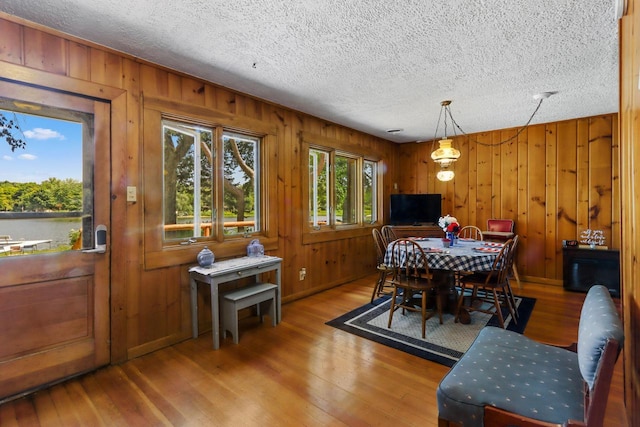 dining room with hardwood / wood-style floors, a textured ceiling, and wooden walls