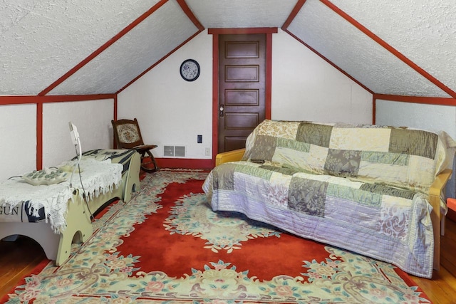 bedroom with wood-type flooring, a textured ceiling, and lofted ceiling