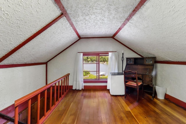 additional living space featuring hardwood / wood-style floors, lofted ceiling, and a textured ceiling