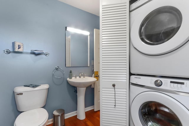 clothes washing area featuring dark hardwood / wood-style floors, sink, and stacked washer and clothes dryer