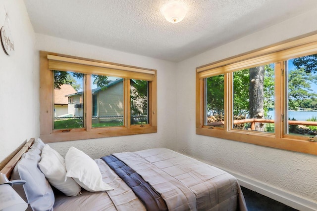 bedroom featuring a textured ceiling and a water view