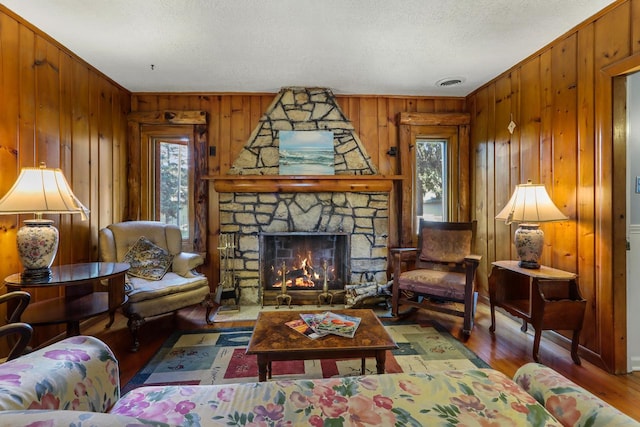 living room with hardwood / wood-style flooring, plenty of natural light, a fireplace, and wooden walls