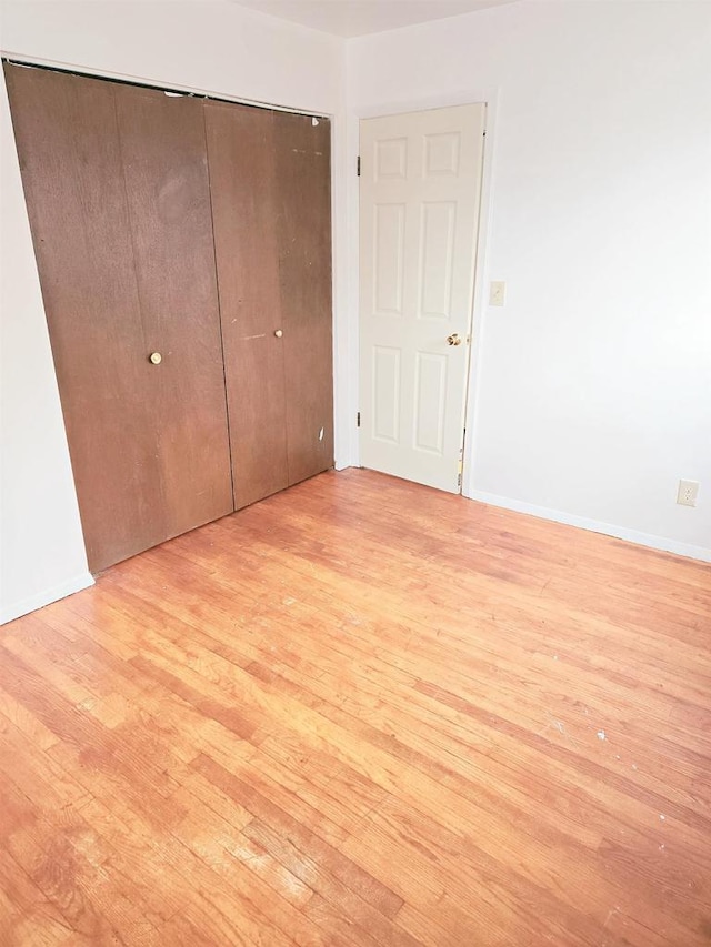 unfurnished bedroom featuring light wood-type flooring and a closet