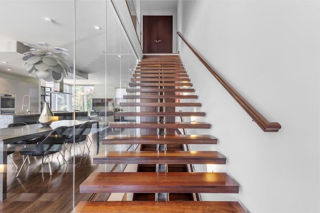 stairs with hardwood / wood-style floors and sink