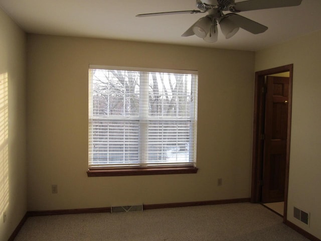 spare room with ceiling fan, plenty of natural light, and light colored carpet