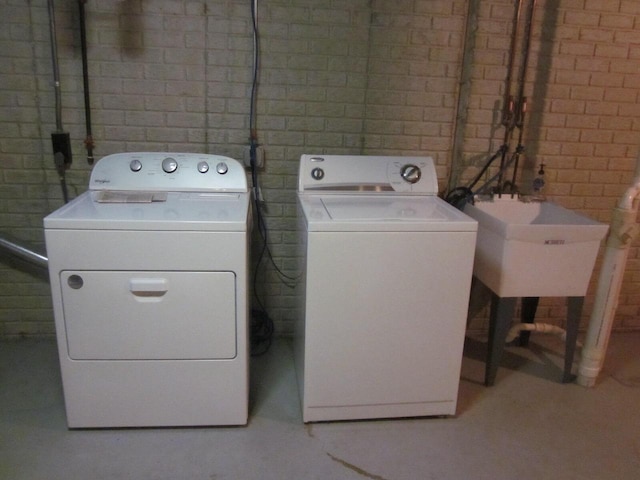 clothes washing area with washing machine and dryer and sink