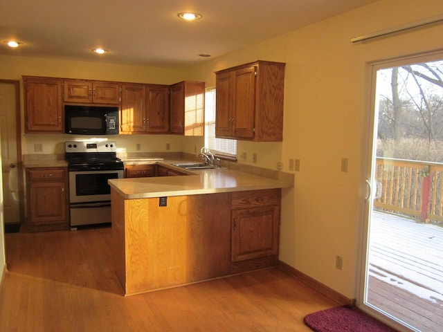 kitchen with stainless steel electric stove, light hardwood / wood-style floors, kitchen peninsula, and sink