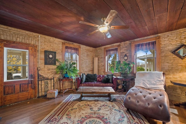 sitting room featuring hardwood / wood-style flooring, ceiling fan, wooden ceiling, and brick wall