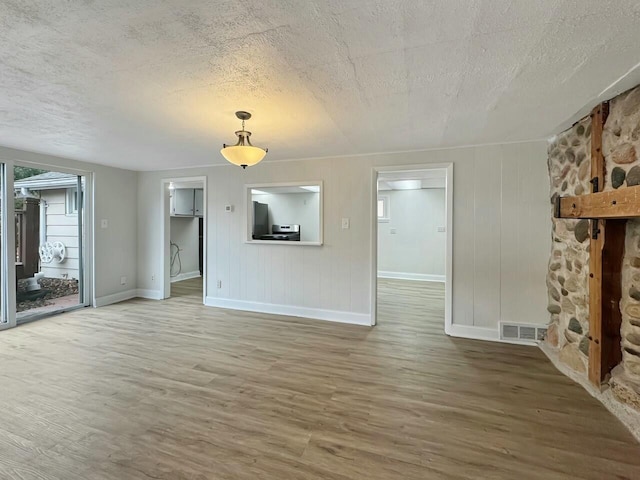 unfurnished living room featuring hardwood / wood-style flooring and a textured ceiling