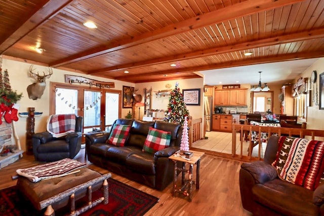 living room featuring a chandelier, beam ceiling, light hardwood / wood-style floors, and wooden ceiling