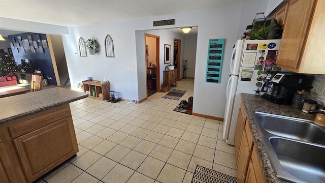 kitchen with sink, light tile patterned flooring, and white refrigerator