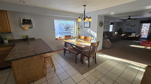 tiled dining room featuring ceiling fan with notable chandelier and a healthy amount of sunlight