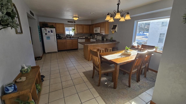 dining space featuring light tile patterned floors, a notable chandelier, and sink