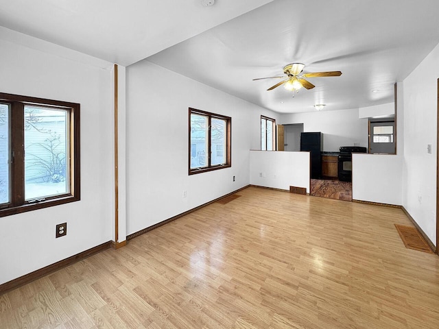 unfurnished living room featuring ceiling fan, a healthy amount of sunlight, and light wood-type flooring