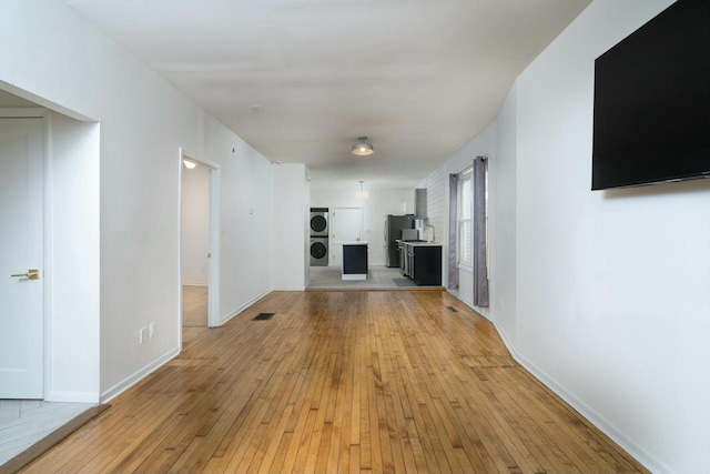 unfurnished living room with light wood-type flooring and stacked washing maching and dryer