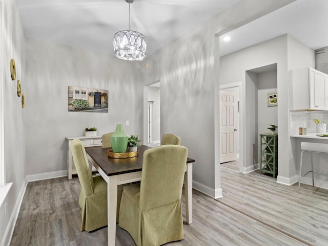 dining space featuring light wood-type flooring and an inviting chandelier