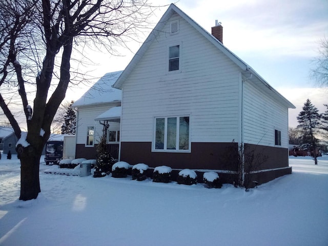 view of snowy exterior with a chimney