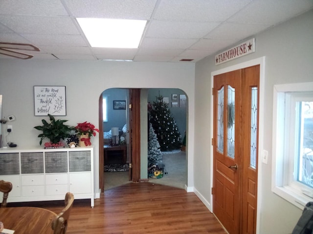 foyer entrance featuring wood finished floors, visible vents, baseboards, arched walkways, and a paneled ceiling