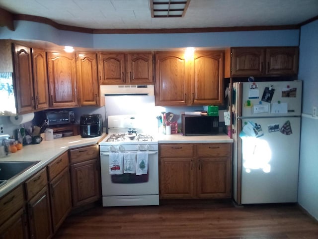 kitchen featuring white appliances, dark wood-style floors, brown cabinetry, light countertops, and under cabinet range hood