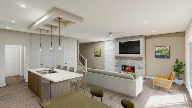 living room with ceiling fan, a stone fireplace, light wood-type flooring, and sink