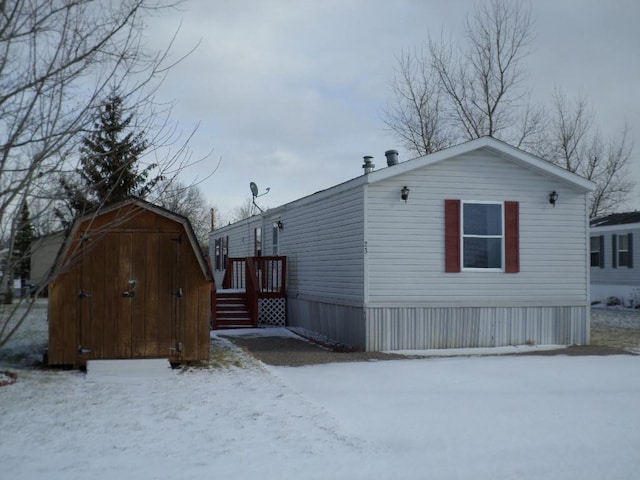 snow covered rear of property featuring a storage shed