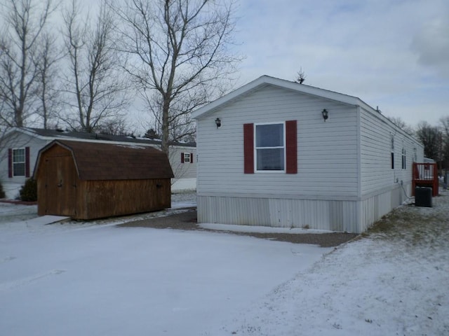 view of snowy exterior with a shed