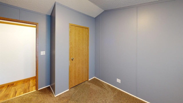 unfurnished bedroom featuring vaulted ceiling, a closet, carpet, and a textured ceiling