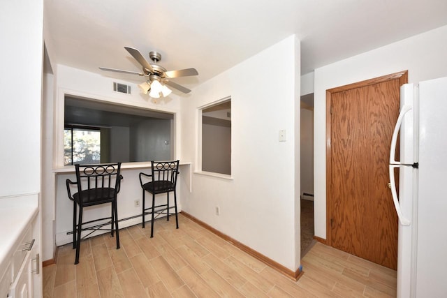 kitchen featuring ceiling fan, white fridge, light hardwood / wood-style flooring, and a baseboard heating unit