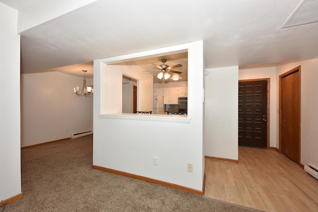 carpeted spare room featuring baseboard heating and ceiling fan with notable chandelier