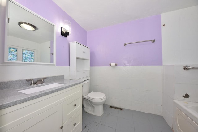 bathroom with vanity, a bathing tub, tile patterned flooring, toilet, and tile walls