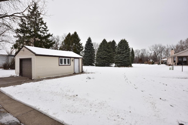 yard covered in snow with a garage and an outbuilding