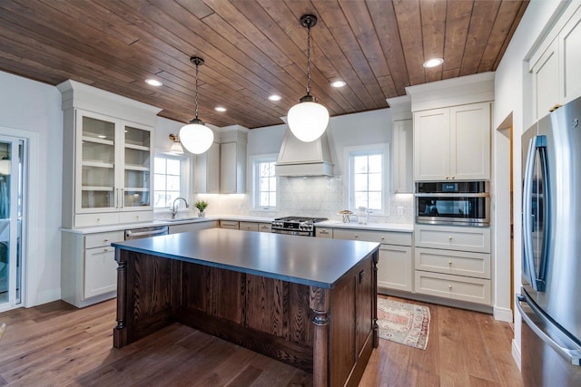 kitchen with pendant lighting, a kitchen island, white cabinets, and appliances with stainless steel finishes