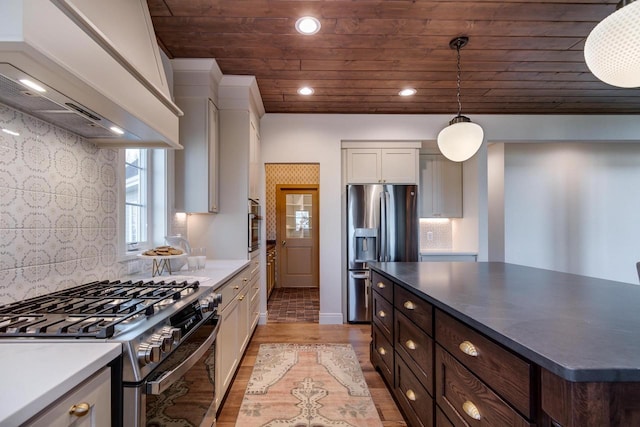 kitchen featuring custom exhaust hood, hanging light fixtures, stainless steel appliances, light hardwood / wood-style floors, and white cabinets